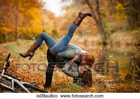 Picture - Romantic young couple fooling around on riverside in autumn. Fotosearch