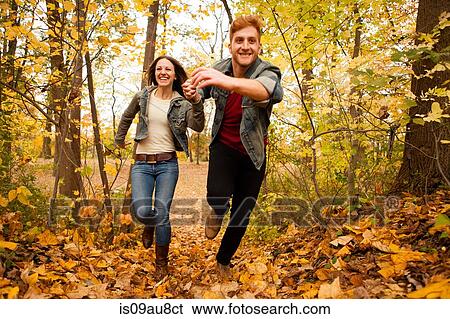 Stock Photograph - Romantic young couple running through autumn forest. Fotosearch