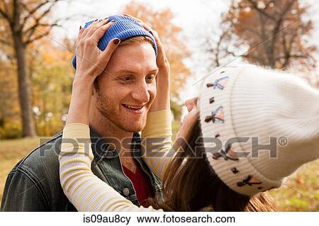 Romantic young woman adjusting boyfriends knit hat in park View Large Photo Image Stock Photo - Romantic young woman adjusting boyfriends knit hat in park. Fotosearch