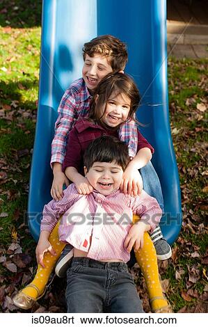 Siblings in a row between each others legs on playground slide smiling View Large Photo Image Stock Photograph - Siblings in a row between each others legs on playground slide smiling. Fotosearch