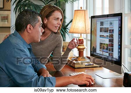 Side view of couple at desk using computer View Large Photo Image Stock Photography - Side view of couple at desk using computer. Fotosearch