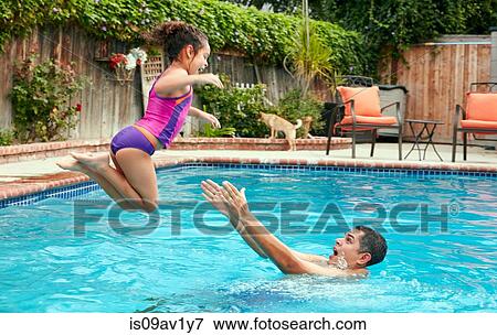 Side view of father catching girl jumping into swimming pool, in mid air View Large Photo Image Stock Photo - Side view of father catching girl jumping into swimming pool, in mid air. Fotosearch