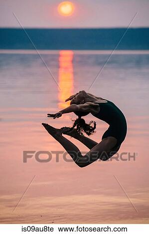 Side view of girl by ocean at sunset, leaping in mid air bending backwards View Large Photo Image Stock Image - Side view of girl by ocean at sunset, leaping in mid air bending backwards. Fotosearch