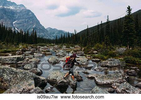 Side view of mid adult woman walking on rocky riverbed, Moraine lake, Banff National Park, Alberta Canada View Large Photo Image Stock Photo - Side view of mid adult woman walking on rocky riverbed, Moraine lake, Banff National Park, Alberta Canada. Fotosearch
