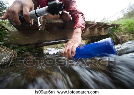Surface view of female hiker with water filter filling water bottle in stream View Large Photo Image Picture - Surface view of female hiker with water filter filling water bottle in stream. Fotosearch
