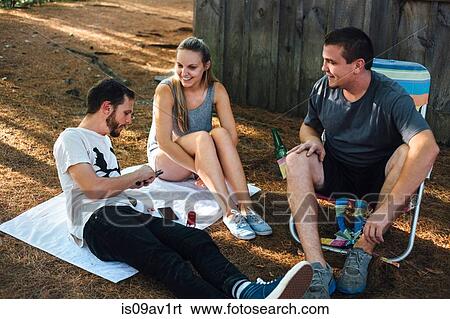 Three adult friends relaxing outside hut in forest View Large Photo Image Stock Photograph - Three adult friends relaxing outside hut in forest. Fotosearch