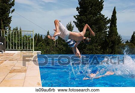 Stock Image - Three boys diving into apartment swimming pool. Fotosearch