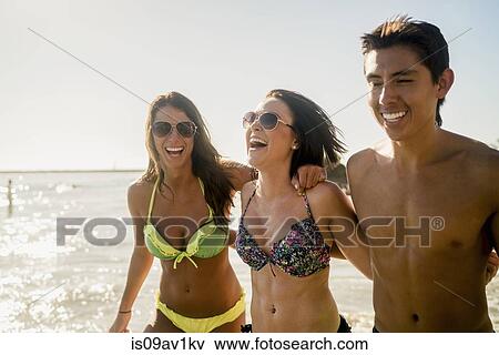 Stock Photo - Three young adult friends strolling on Newport Beach, California, USA. Fotosearch