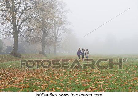 Stock Photography - Three young girls walking through field in autumn. Fotosearch