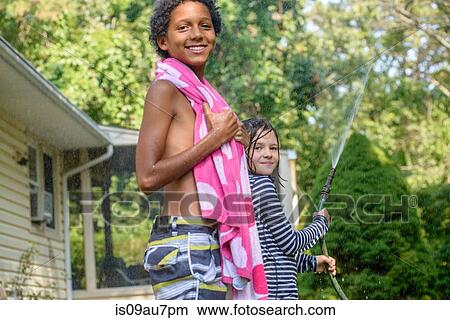 Picture - Two children in garden, playing with garden hose. Fotosearch
