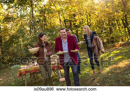 Stock Photograph - Two mature couples carrying food for garden party. Fotosearch