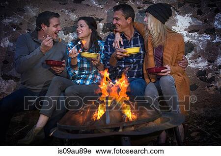 Two mature couples eating in front of campfire at night View Large Photo Image Stock Image - Two mature couples eating in front of campfire at night. Fotosearch
