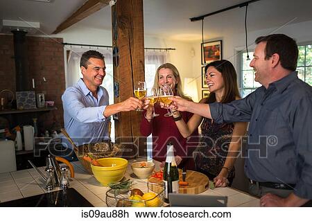 Stock Image - Two mature couples making a toast at dinner party. Fotosearch