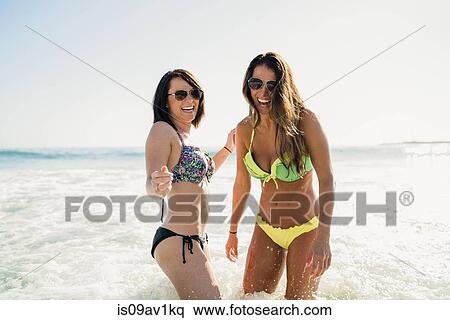 Stock Photography - Two young female friends paddling in sea at Newport Beach, California, USA. Fotosearch