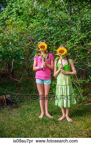 Stock Photography - Two young girls holding sunflowers in front of faces. Fotosearch