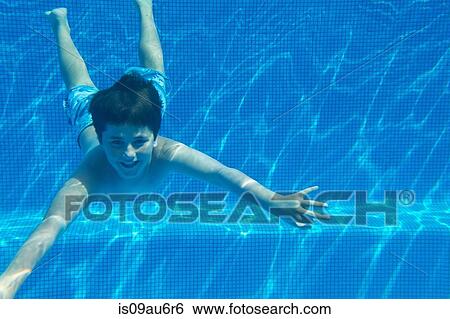 Stock Photograph - Underwater view of boy underwater swimming in swimming pool. Fotosearch