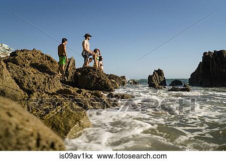 Stock Photo - Young adult friends exploring rocks on Newport Beach, California, USA. Fotosearch