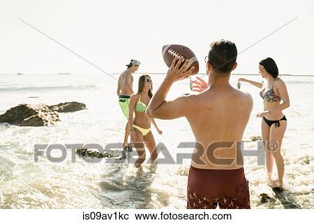 Young adult friends playing American football in sea at Newport Beach, California, USA View Large Photo Image Stock Image - Young adult friends playing American football in sea at Newport Beach, California, USA. Fotosearch