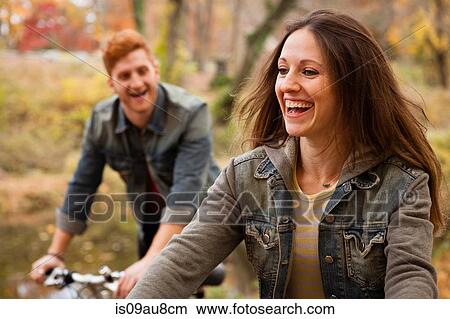 Picture - Young couple cycling along riverside in autumn. Fotosearch
