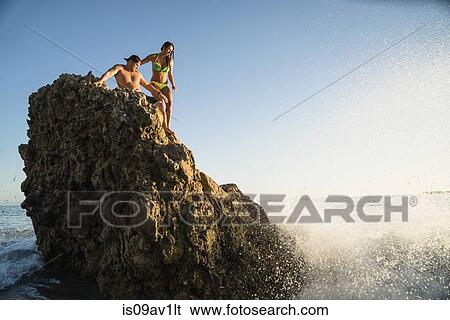 Young couple on rock with waves splashing at Newport Beach, California, USA View Large Photo Image Stock Photograph - Young couple on rock with waves splashing at Newport Beach, California, USA. Fotosearch
