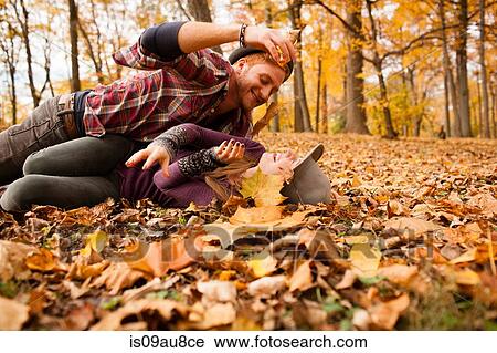 Young couple play fighting with autumn leaves in forest View Large Photo Image Stock Image - Young couple play fighting with autumn leaves in forest. Fotosearch