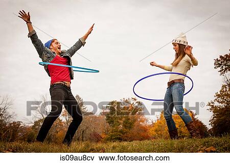 Young couple playing with plastic hoops in autumn park View Large Photo Image Stock Photo - Young couple playing with plastic hoops in autumn park. Fotosearch