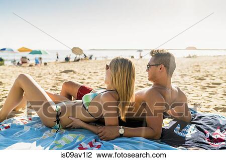 Stock Image - Young couple sunbathing on Newport Beach, California, USA. Fotosearch