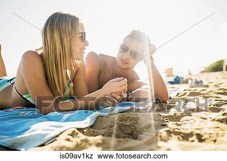 Stock Photo - Young couple sunbathing on Newport Beach, California, USA. Fotosearch