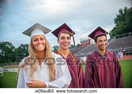 Stock Image - Young female and male graduates at graduation ceremony. Fotosearch