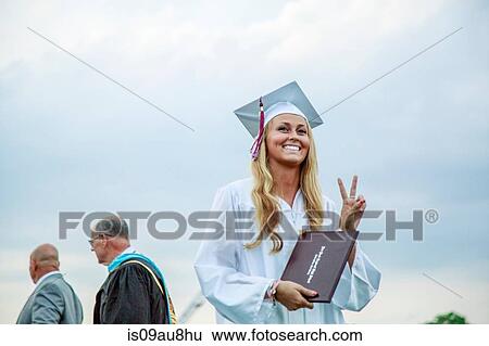 Young female graduate making peace sign at graduation ceremony View Large Photo Image Stock Photograph - Young female graduate making peace sign at graduation ceremony. Fotosearch