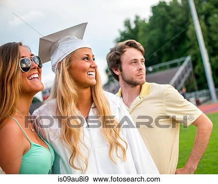 Stock Photo - Young female graduate with sister and brother at graduation ceremony. Fotosearch