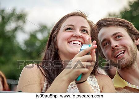Stock Photography - Young man and sister clapping at graduation ceremony. Fotosearch