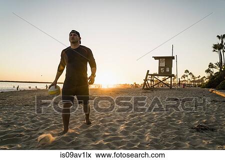 Stock Photo - Young man playing beach volleyball at sunset, Newport Beach, California, USA. Fotosearch