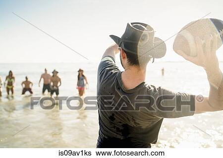 Young man throwing American football ball to friends in sea at Newport Beach, California, USA View Large Photo Image Stock Photograph - Young man throwing American football ball to friends in sea at Newport Beach, California, USA. Fotosearch