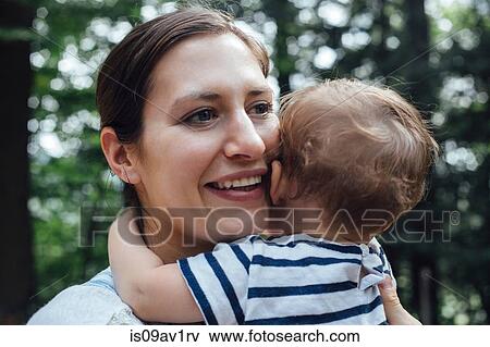 Stock Photo - Young woman and baby daughter hugging in forest. Fotosearch