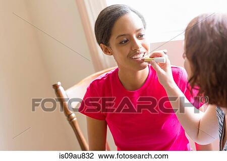 Young woman applying lipstick to friends lips View Large Photo Image Stock Image - Young woman applying lipstick to friends lips. Fotosearch