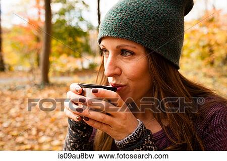 Young woman drinking coffee in autumn forest View Large Photo Image Stock Photo - Young woman drinking coffee in autumn forest. Fotosearch