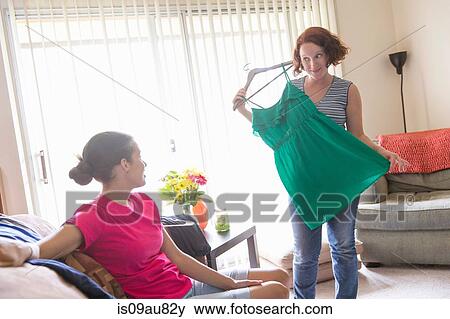 Young woman in living room showing friend dress View Large Photo Image Stock Photo - Young woman in living room showing friend dress. Fotosearch