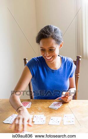 Young woman sitting at dining table playing cards smiling View Large Photo Image Stock Photograph - Young woman sitting at dining table playing cards smiling. Fotosearch