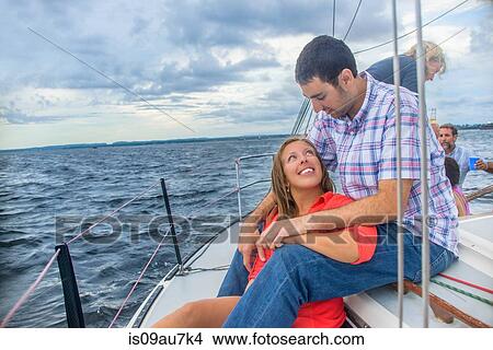 Young woman sitting between young mans legs on sailboat, face to face smiling View Large Photo Image Picture - Young woman sitting between young mans legs on sailboat, face to face smiling. Fotosearch