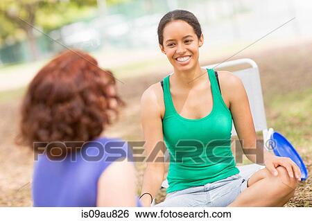 Young woman sitting crossed legs tallking to friend, smiling View Large Photo Image Stock Photograph - Young woman sitting crossed legs tallking to friend, smiling. Fotosearch