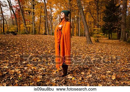 Young woman wrapped in orange blanket in forest View Large Photo Image Stock Photograph - Young woman wrapped in orange blanket in forest. Fotosearch