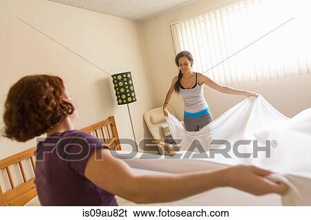 Young women in bedroom making bed View Large Photo Image Stock Photograph - Young women in bedroom making bed. Fotosearch
