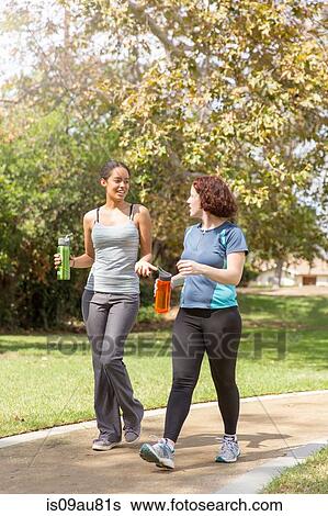 Young women out walking wearing sports clothing carrying water bottles talking View Large Photo Image Stock Photograph - Young women out walking wearing sports clothing carrying water bottles talking. Fotosearch