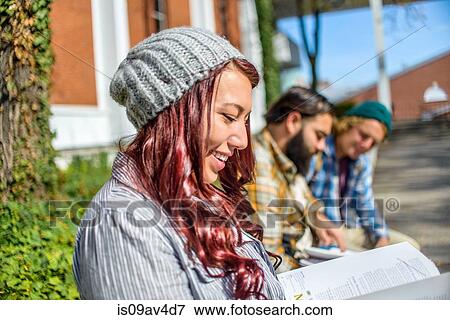 Adult college students reading books on campus wall View Large Photo Image Stock Photo - Adult college students reading books on campus wall. Fotosearch