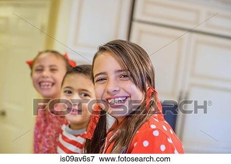 Stock Photo - Angled view of children wearing pyjamas looking at camera smiling. Fotosearch
