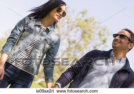 Stock Image - Angled view of couple wearing sunglasses. Fotosearch