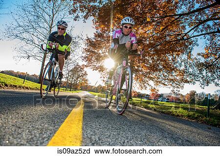 Angled view of cyclists cycling on road View Large Photo Image Stock Image - Angled view of cyclists cycling on road. Fotosearch