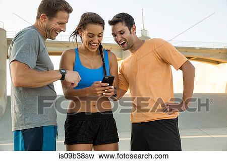 Athletes laughing at message on mobile phone, Van Nuys, California, USA View Large Photo Image Stock Photo - Athletes laughing at message on mobile phone, Van Nuys, California, USA. Fotosearch