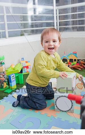 Stock Photography - Baby boy stacking playing blocks at home. Fotosearch